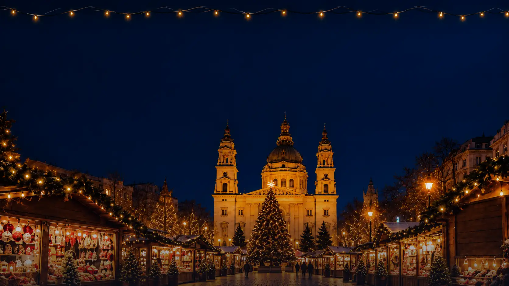 Christmas market in front of St Stephen's Basilica in Budapest — lit stalls and a Christmas tree in the evening